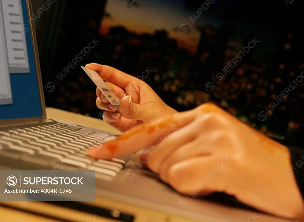 Hands with henna on keypad Holding Credit Card