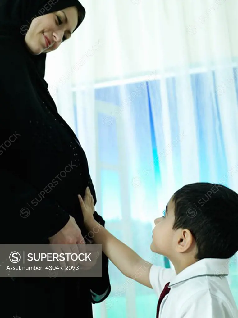 Low angle view of the child touch the tummy of his pregnant mother.