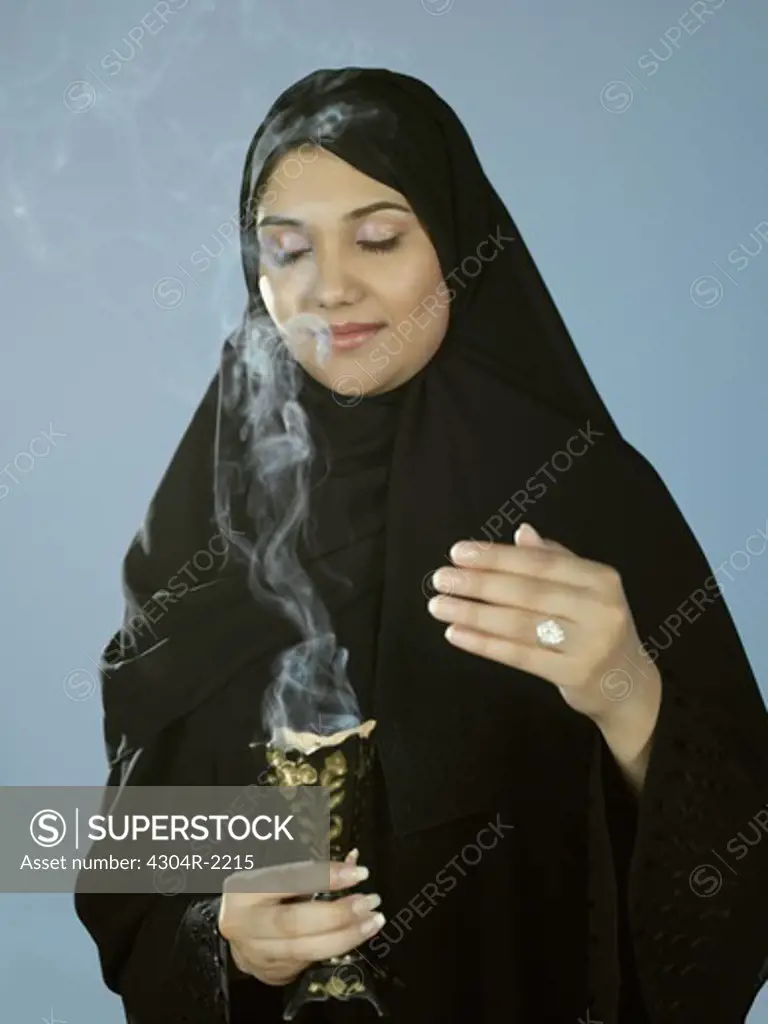 An Arab lady smells the aroma of incense