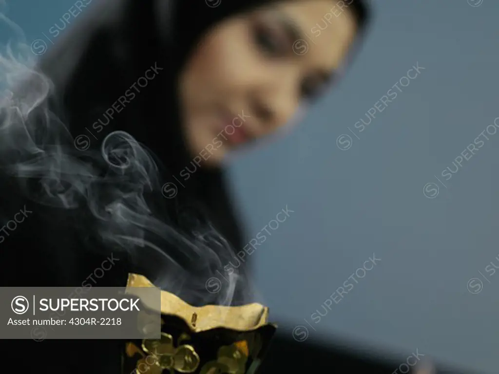 An Arab lady smells the aroma of incense