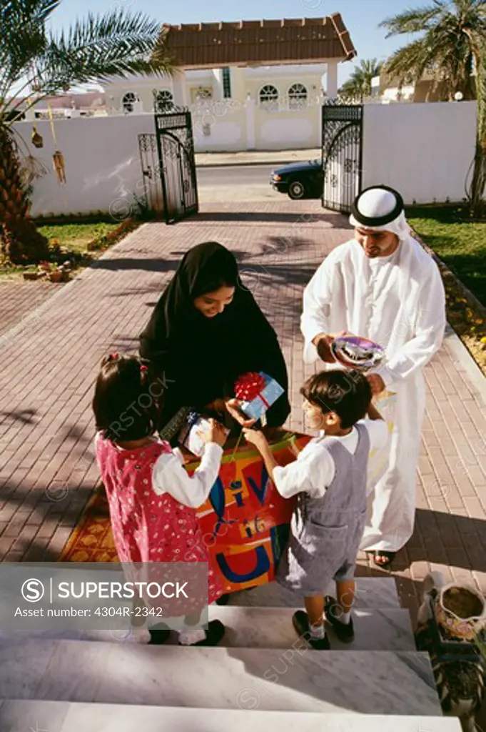 Parents give gifts to their children after returning from shopping.