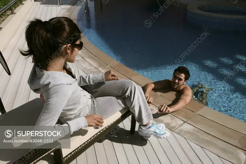 Young lady looking at man in a swimming pool.