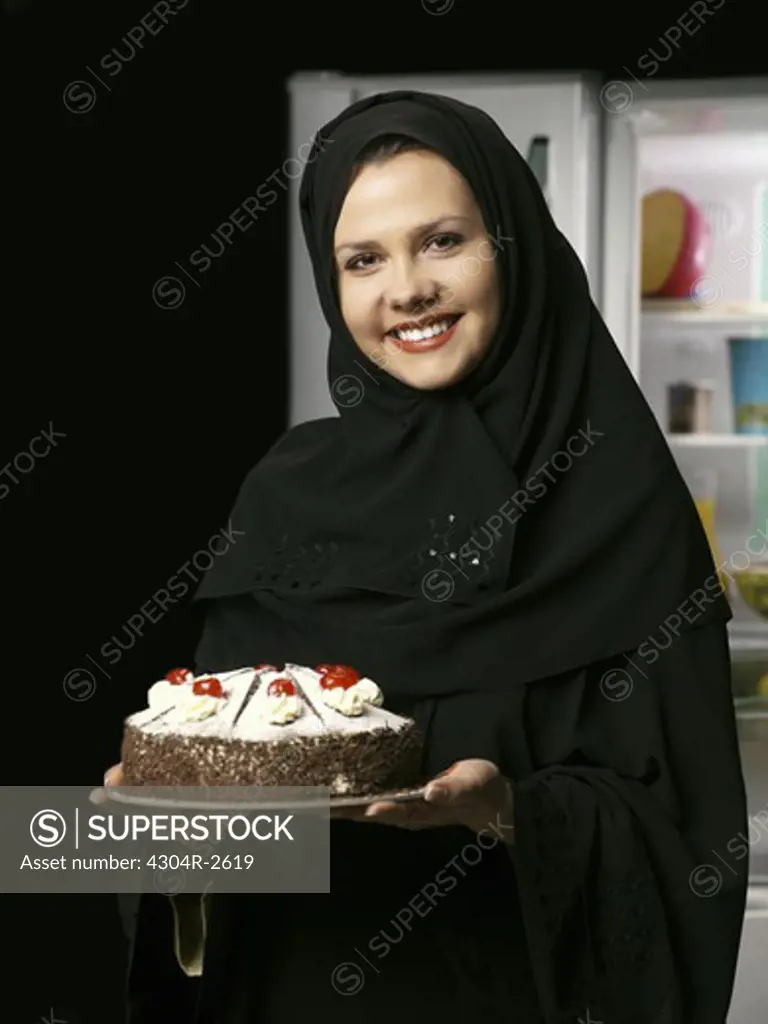 Arab lady holding a cake.