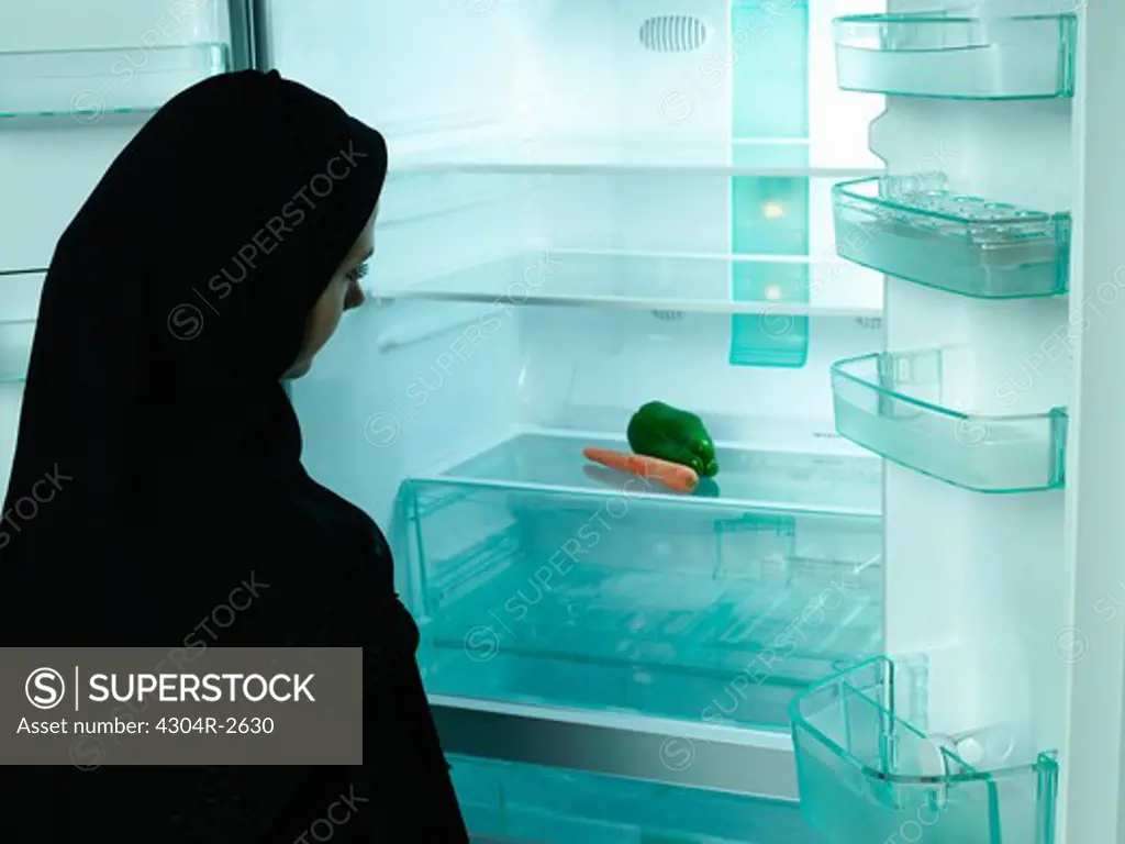 Arab lady looking at refrigerator.