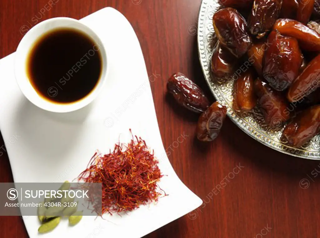 Cup of coffee, Saffron & cardamom - ingredients of Arabic coffee with plate of dates.