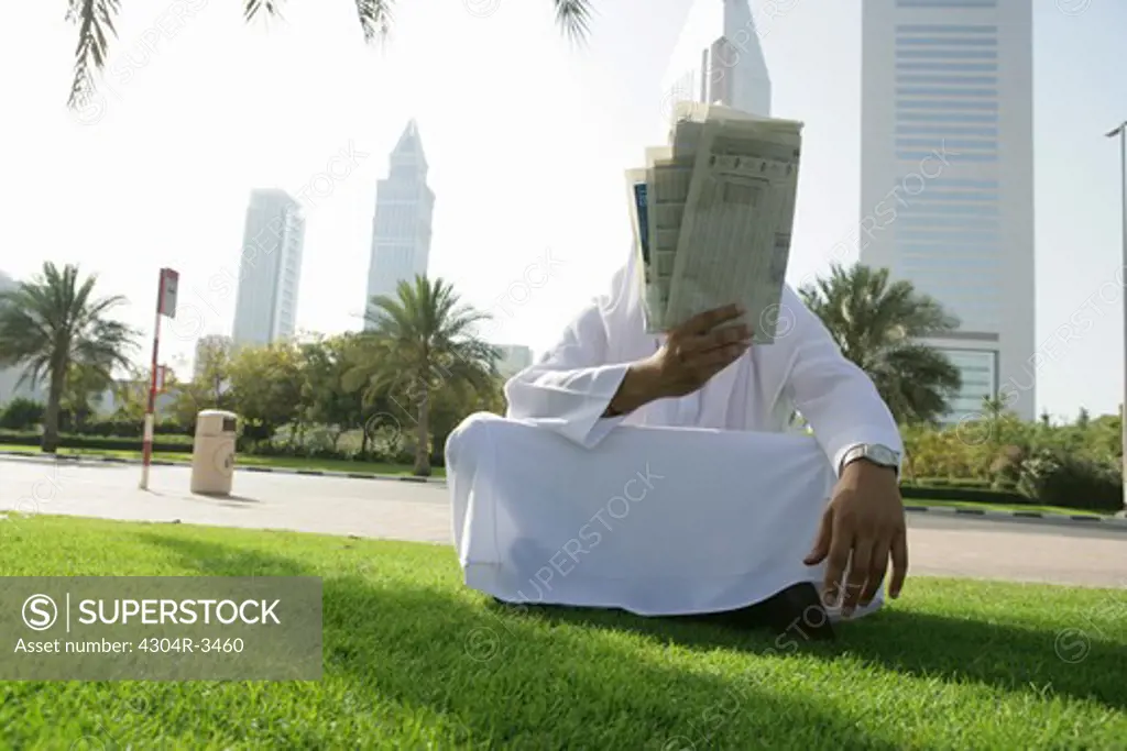 Arab Man read the newspaper under the Palm Tree