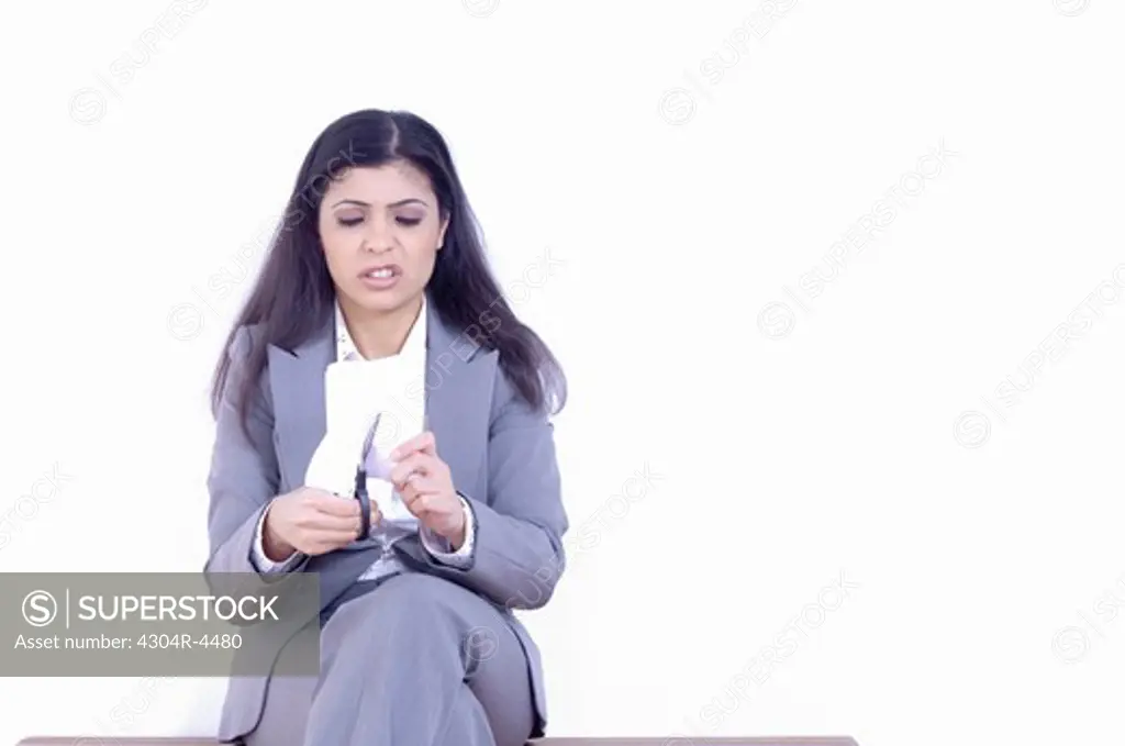 Upset lady sitting on bench, cutting a paper