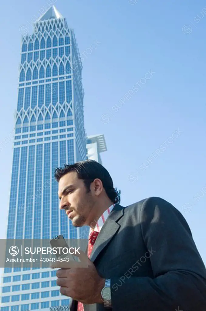 Young man holding on cell phone with skyscrapers in the background