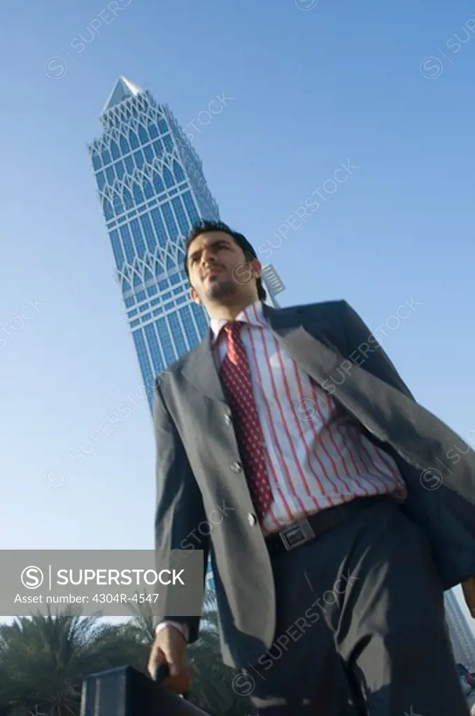 Young man walking outdoors with skyscrapers in the background