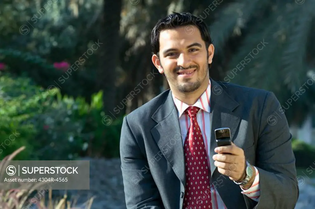Young man holding a cell phone and smiling