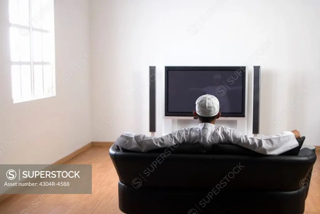 Young Arab man watching TV