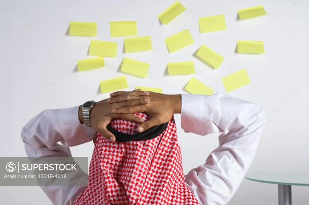 Young Arab man looking at a lot of post-it notes