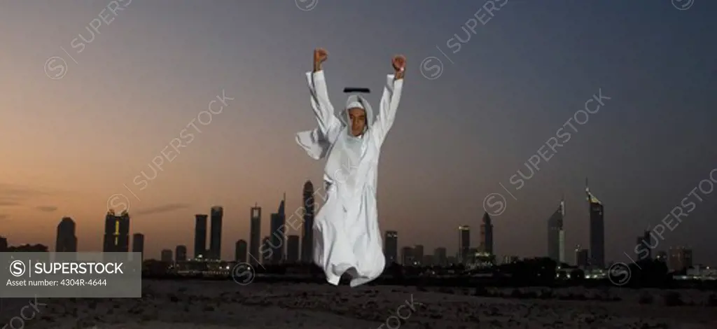 Young Arab man jumping with joy with Dubai City in the background