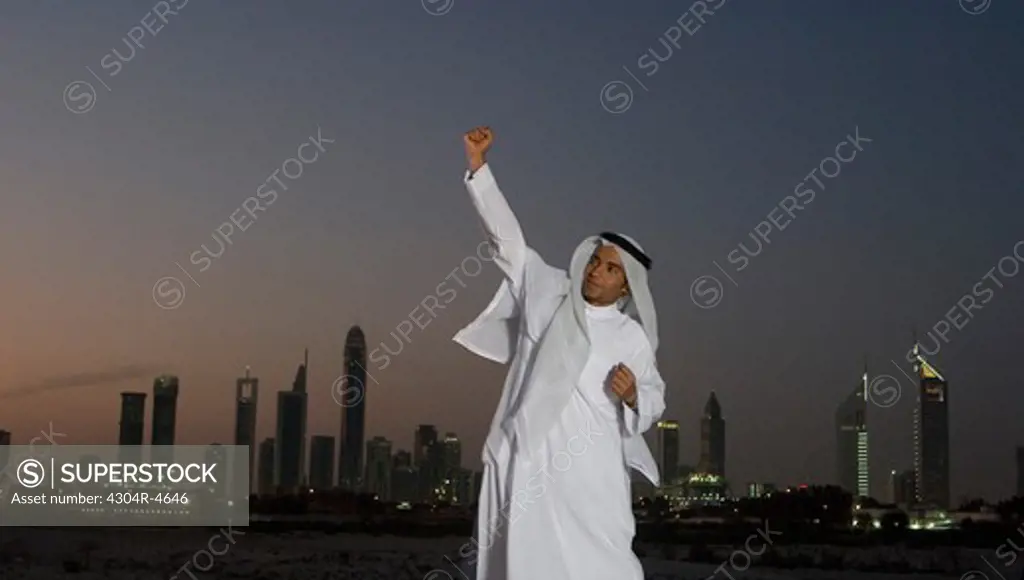 Young Arab man jumping with joy with Dubai City in the background