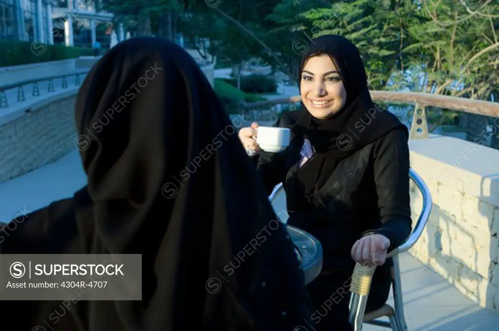 Two Arab Ladies talking in a cafe outdoors