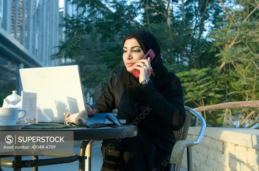 Arab Lady outdoors talking on a cell phone