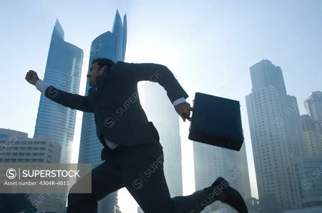 Businessman running, towers seen through the mist in the background