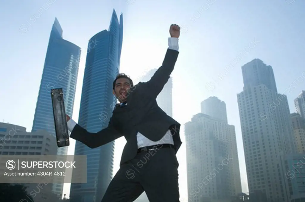 Businessman jumping with joy, towers seen through the mist in the background