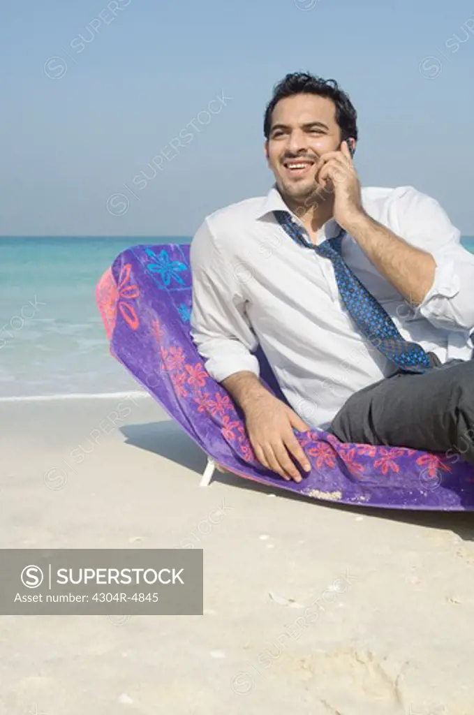 Businessman talking on the cell phone on the beach
