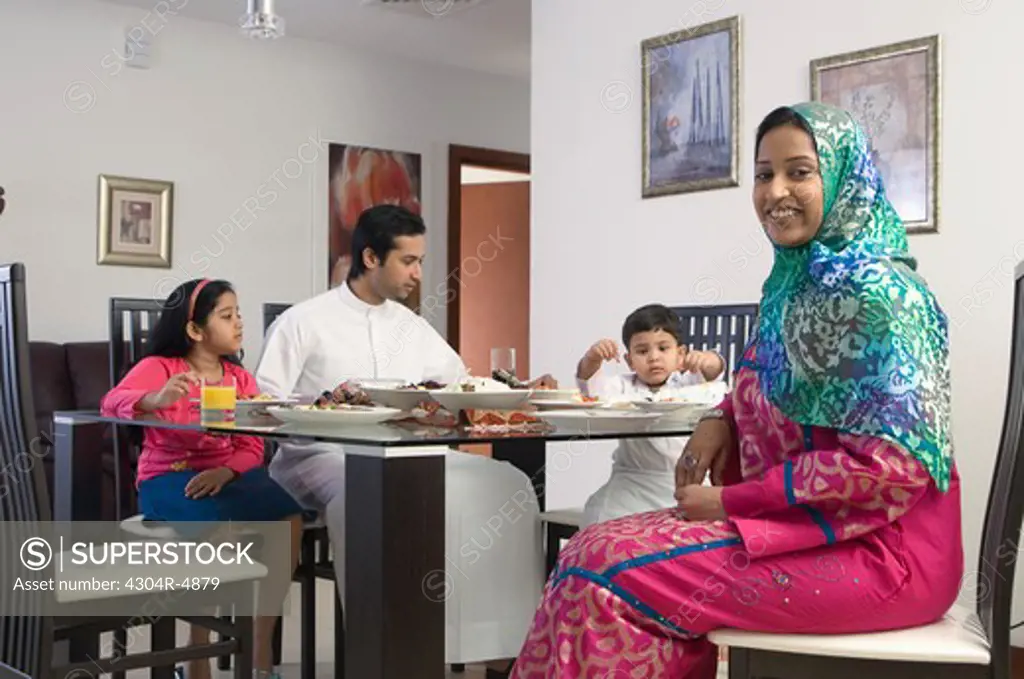 Arab Family of four dining while woman smiles