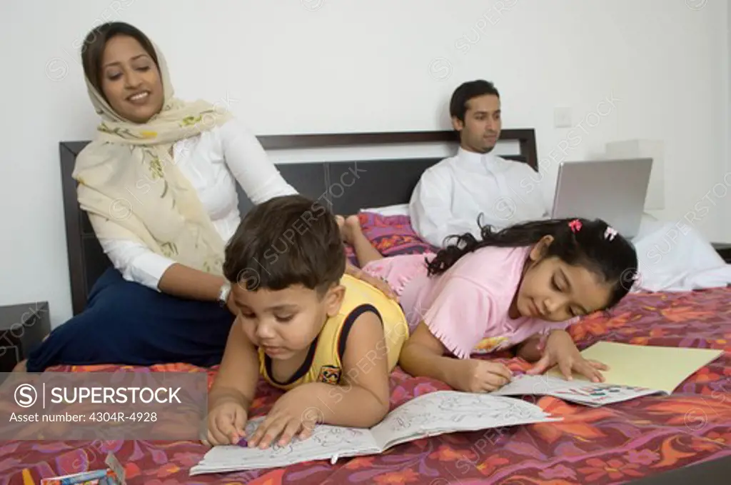 Children reading on the bed while parents watch