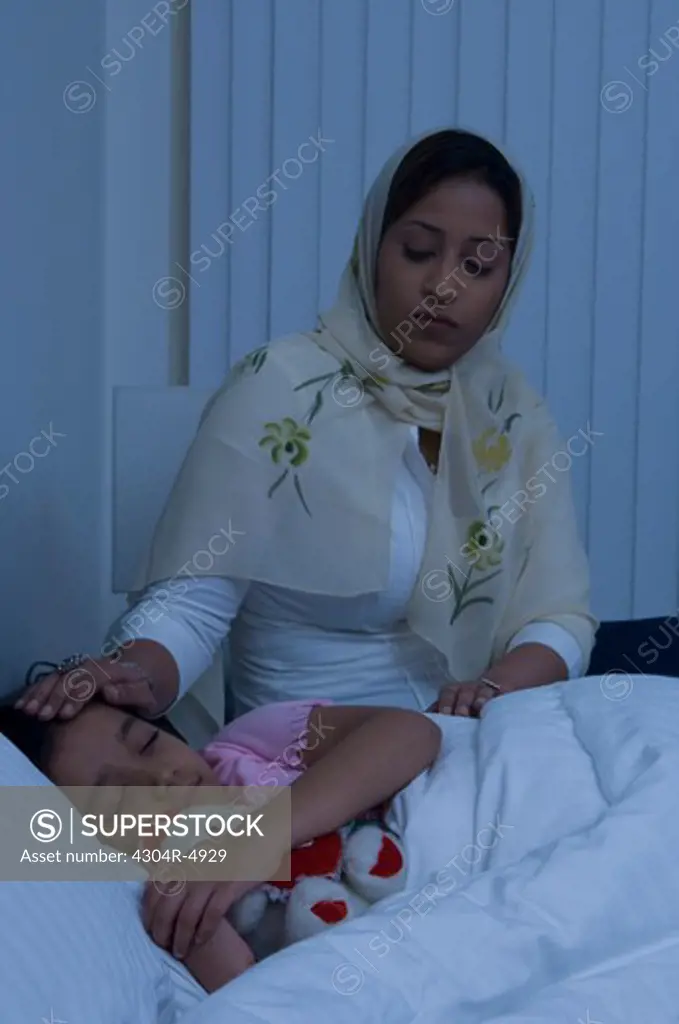 Mother puts daughter to bed