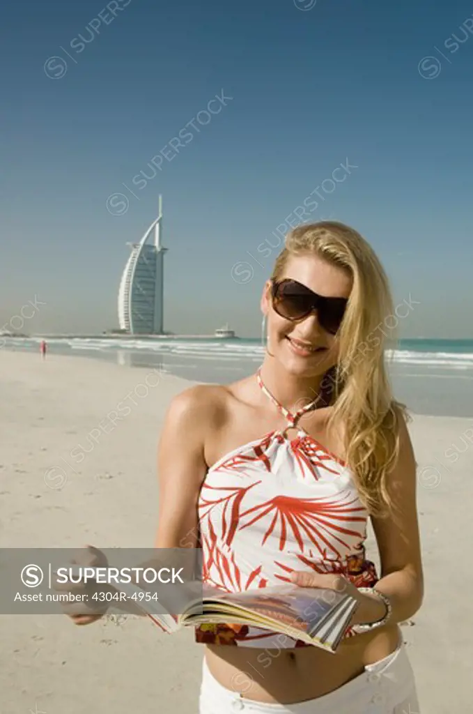 Young lady with guide book in front of the famous landmark of Dubai