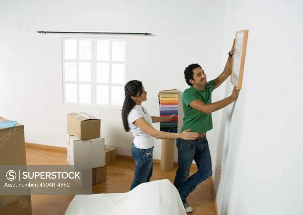 Young couple deciding position to hang painting