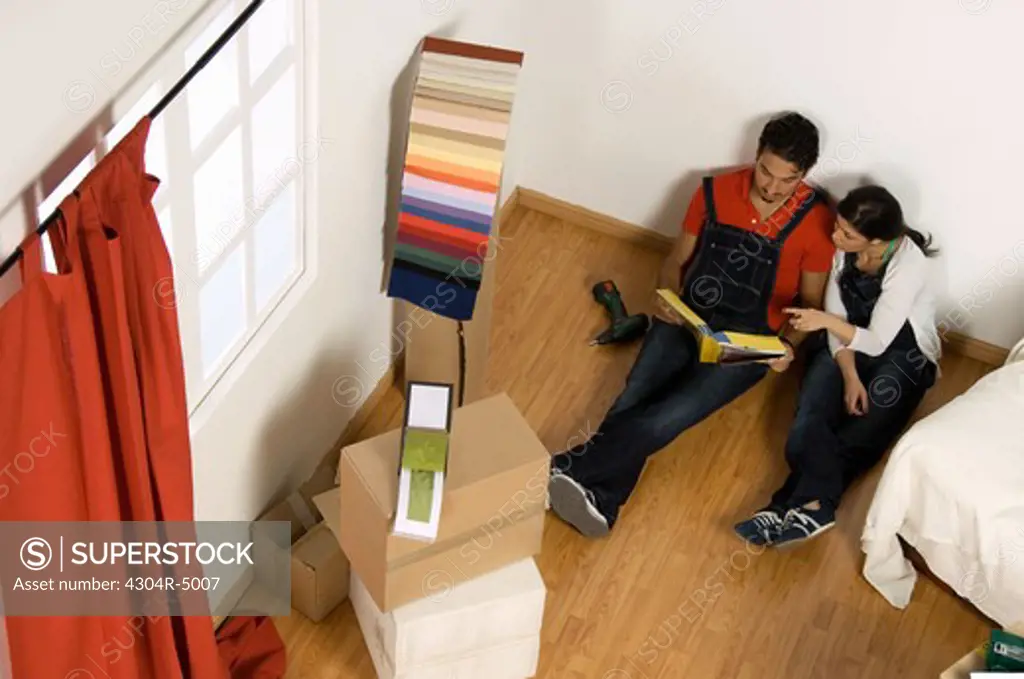 Young couple referring to address book for home improvement