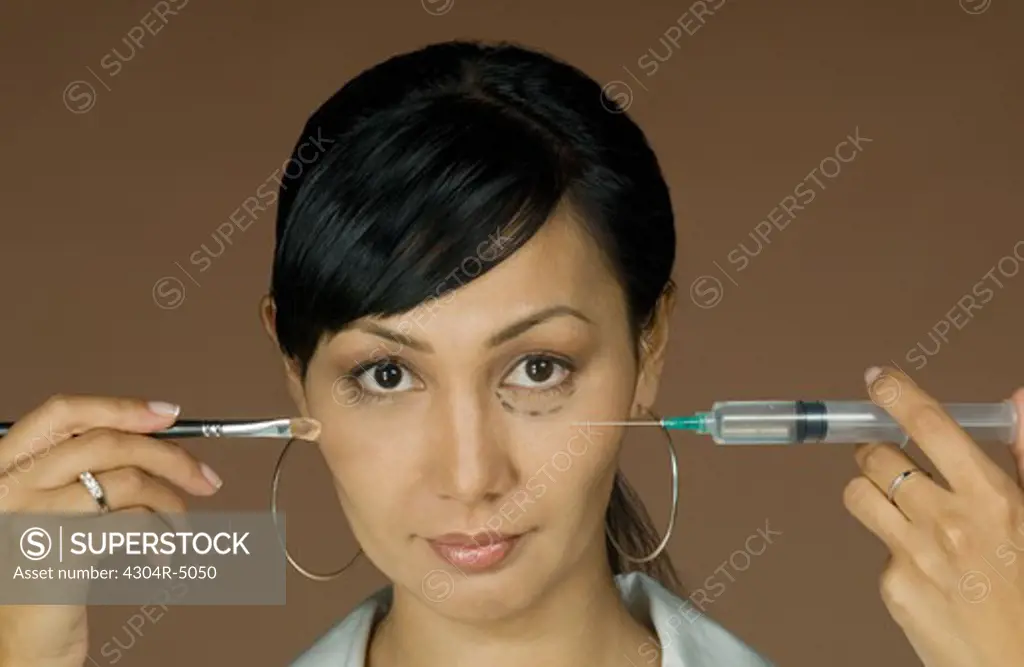 Young woman holding a syringe and make-up brush