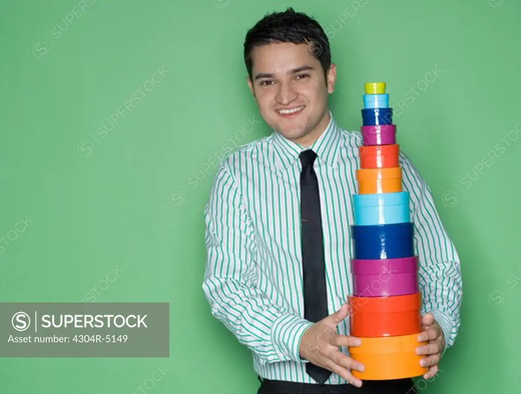 Young man holding a stack of colorful boxes