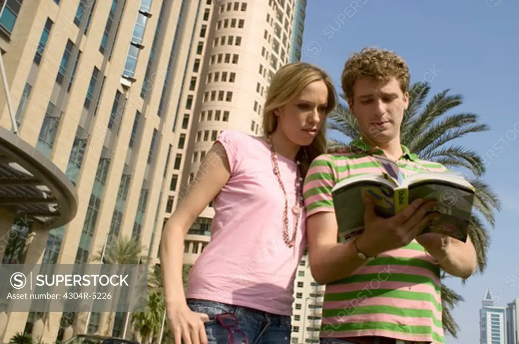 Couple looking at travel guide, United Arab Emirates