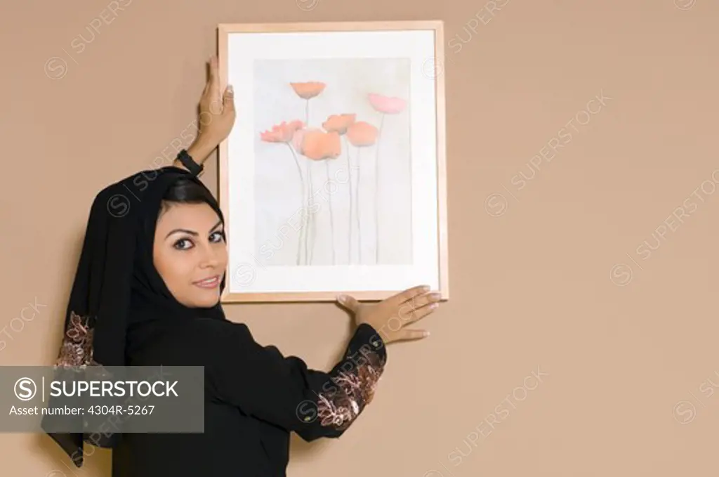 Young woman adjusting picture frame, portrait