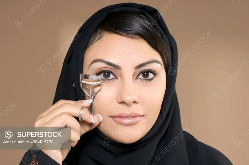 Young woman using eyelash curler, close-up ,portrait
