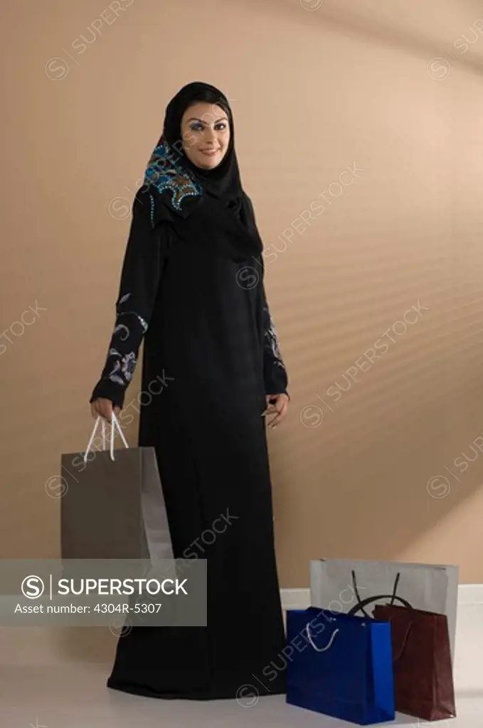Young woman holding shopping bag, smiling, portrait