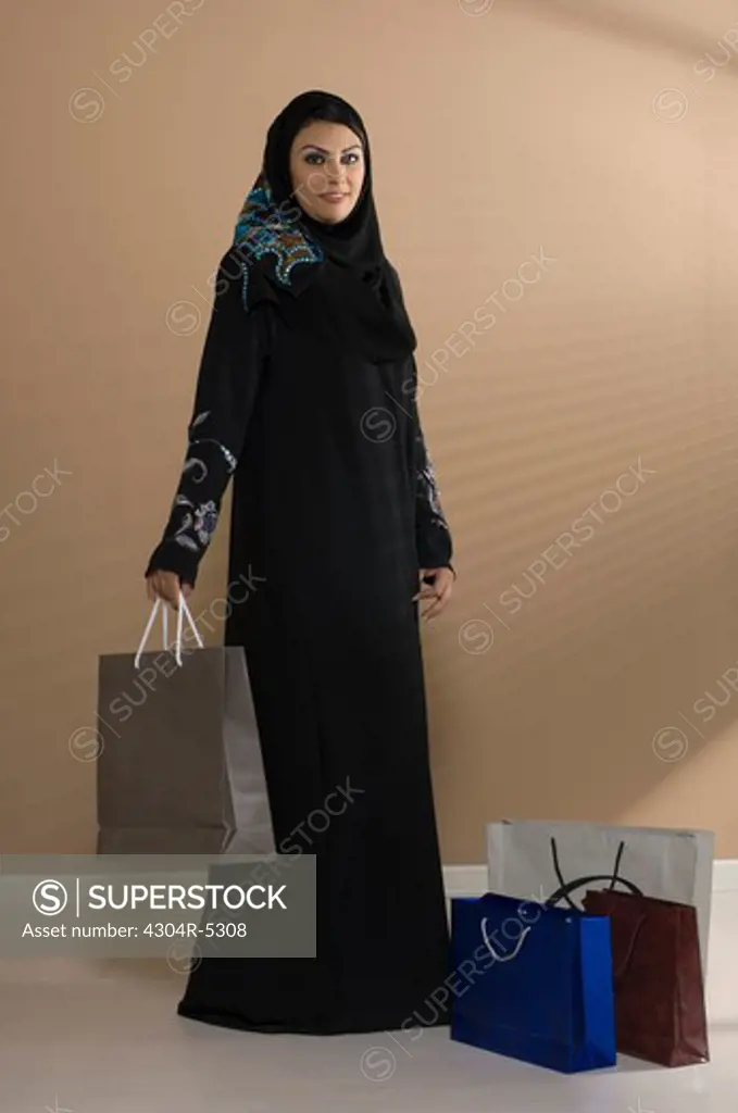 Young woman holding shopping bag, smiling, portrait