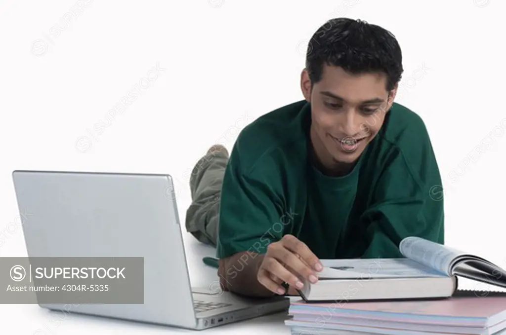 Young man with laptop reading book