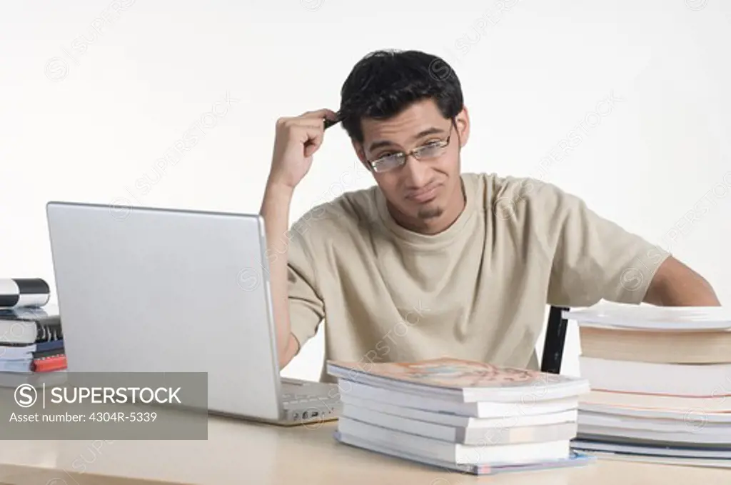 Young man sitting in front of laptop and books