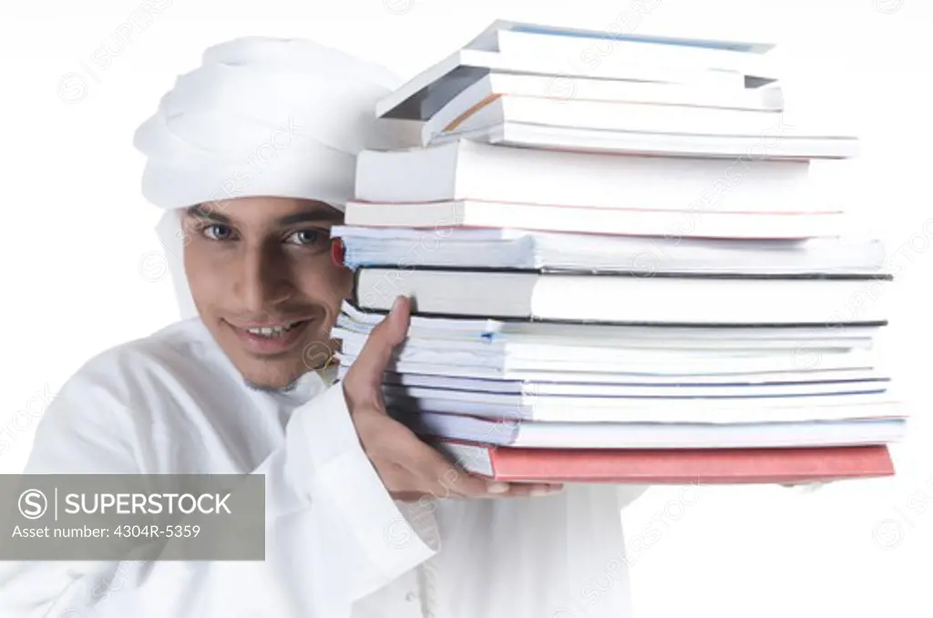 Young man carrying pile of books, portrait, close-up
