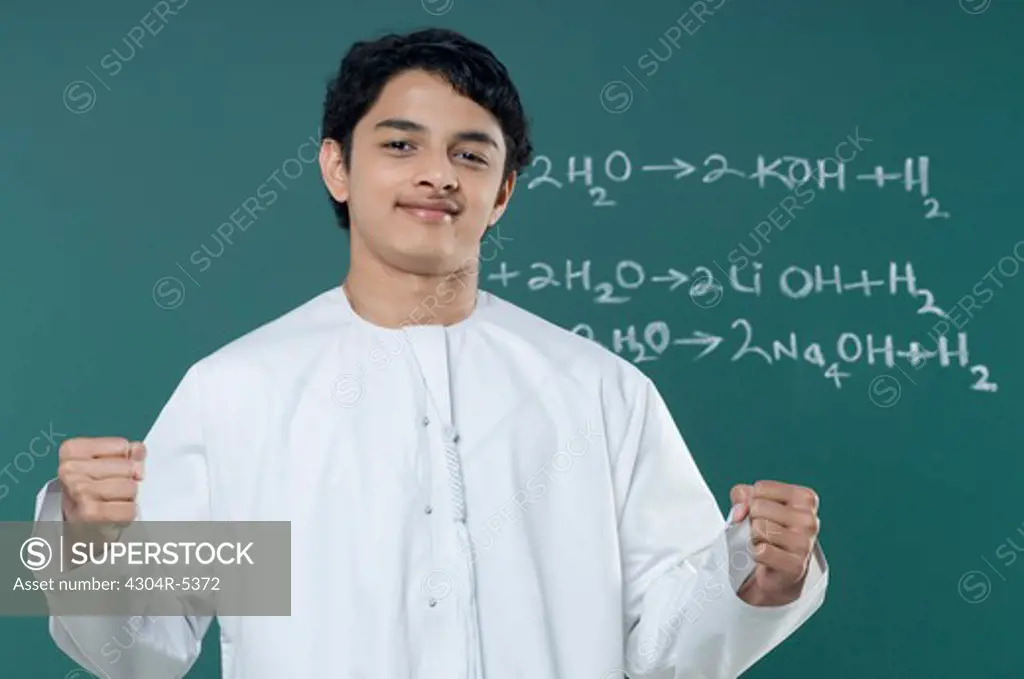 Teenage boy gesturing by blackboard, portrait