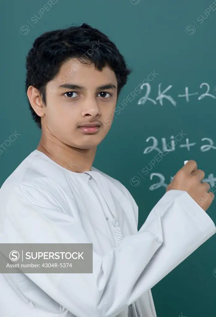 Teenage boy solving equations on blackboard
