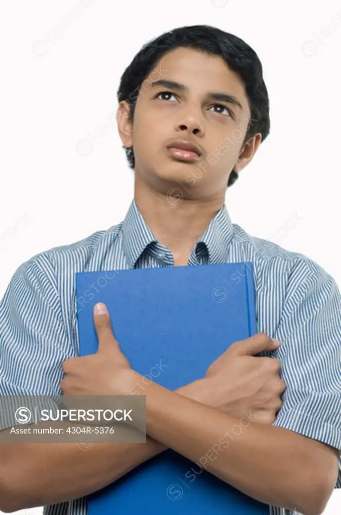Teenage boy with book looking up