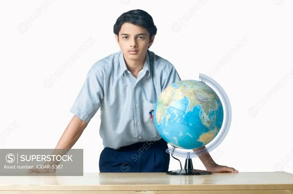 Teenage boy standing beside globe, portrait