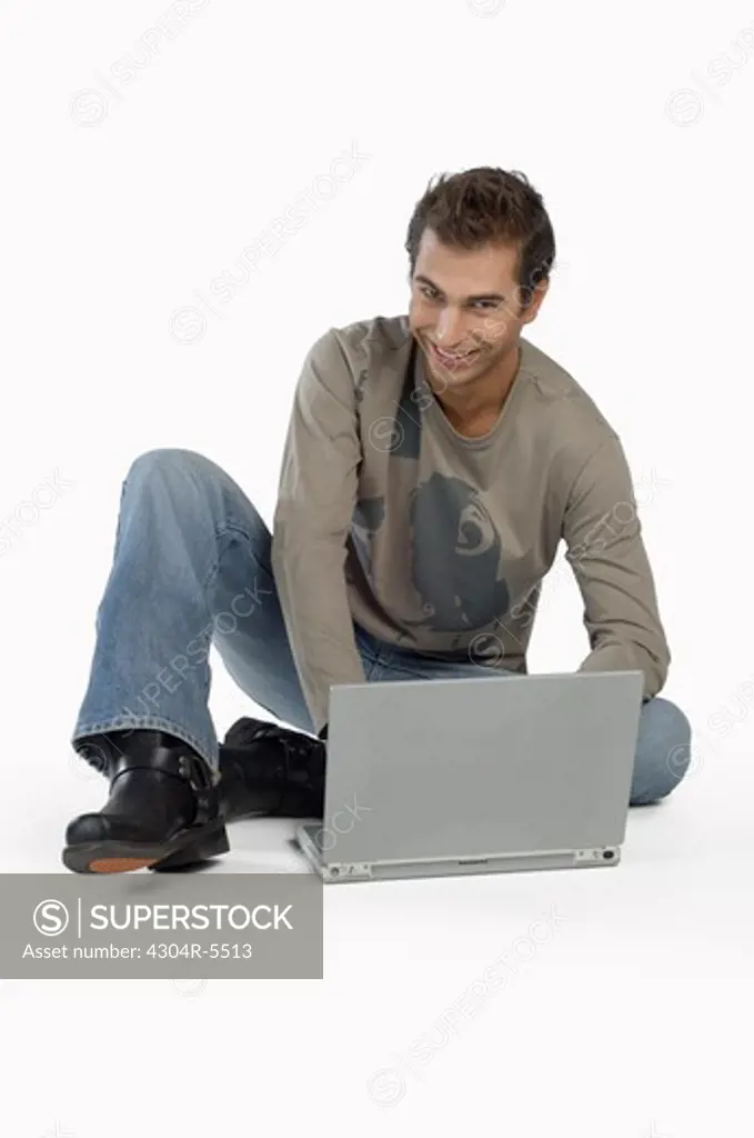 Young man using laptop, smiling, portrait
