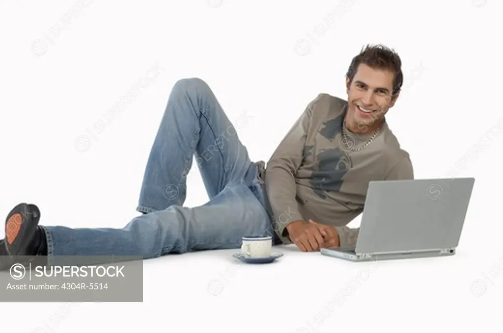 Young man with laptop, smiling, portrait