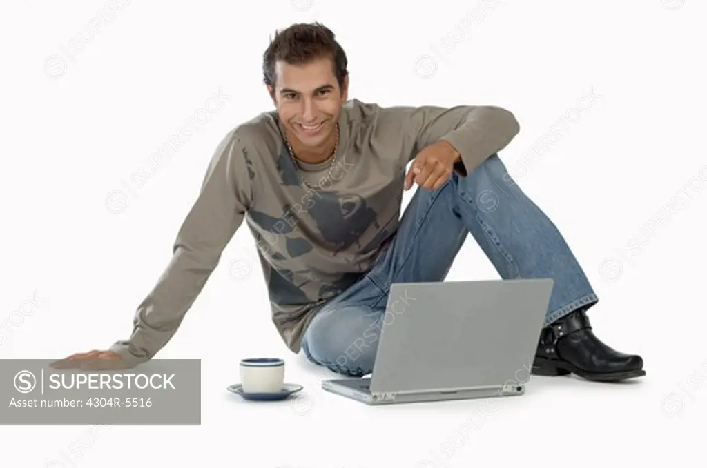 Young man with laptop, smiling, portrait