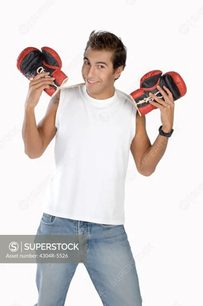 Young man holding boxing gloves, smiling, portrait