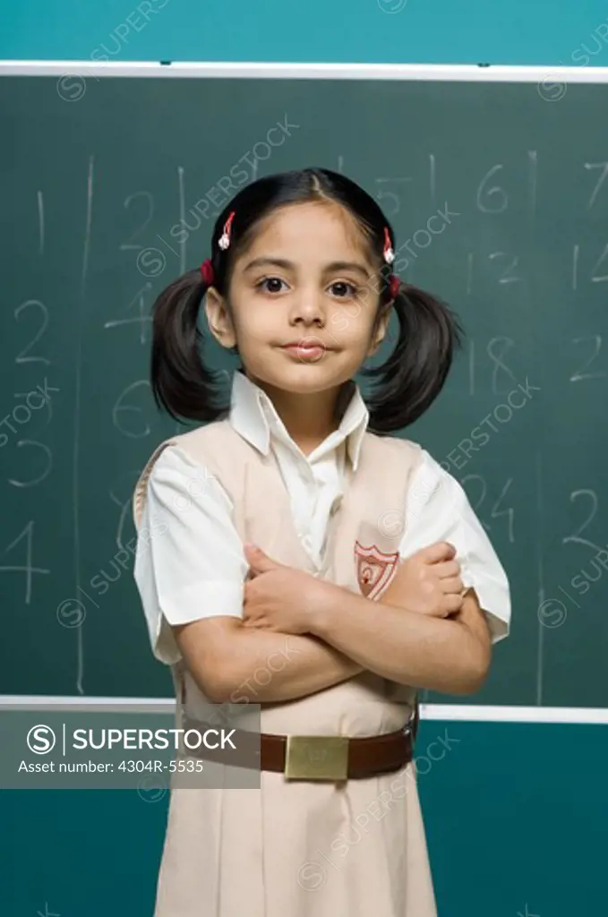 Girl (6-7) standing in classroom, smiling, portrait