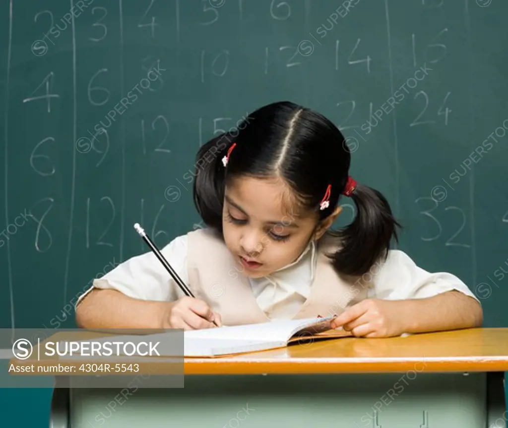 Girl (6-7) holding pencil, writing