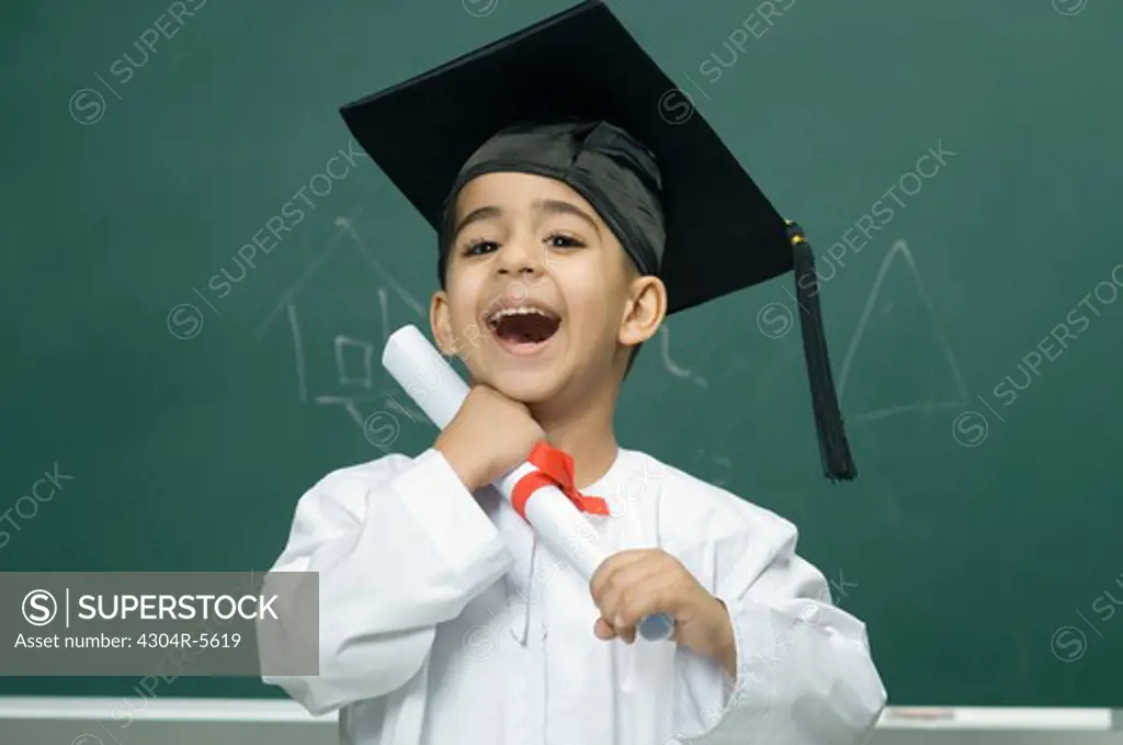 Boy (4-5) wearing mortarboard and holding degree, portrait